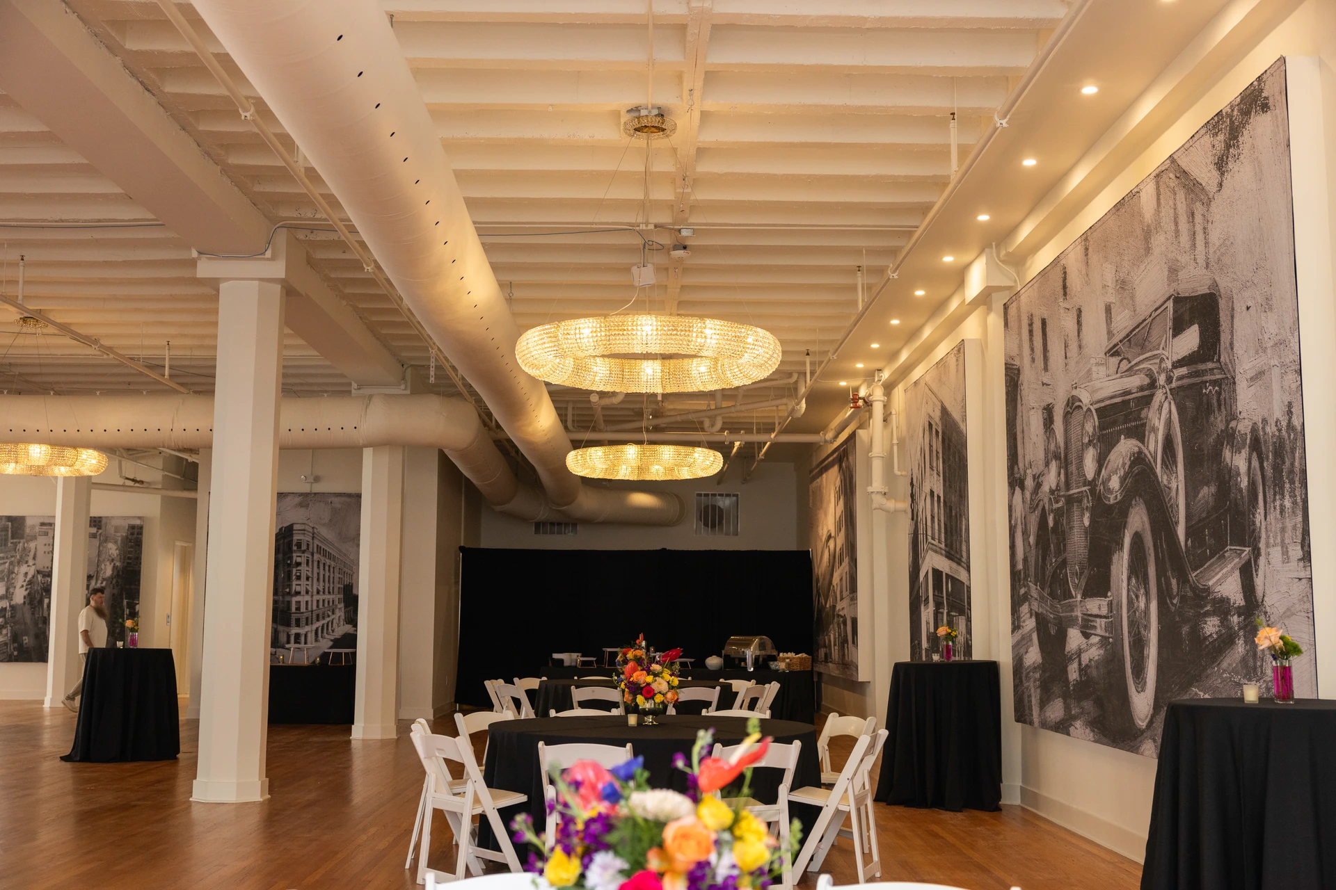A dining arrangement inside Grand Ballroom with chairs, flowers and artwork along the wall.