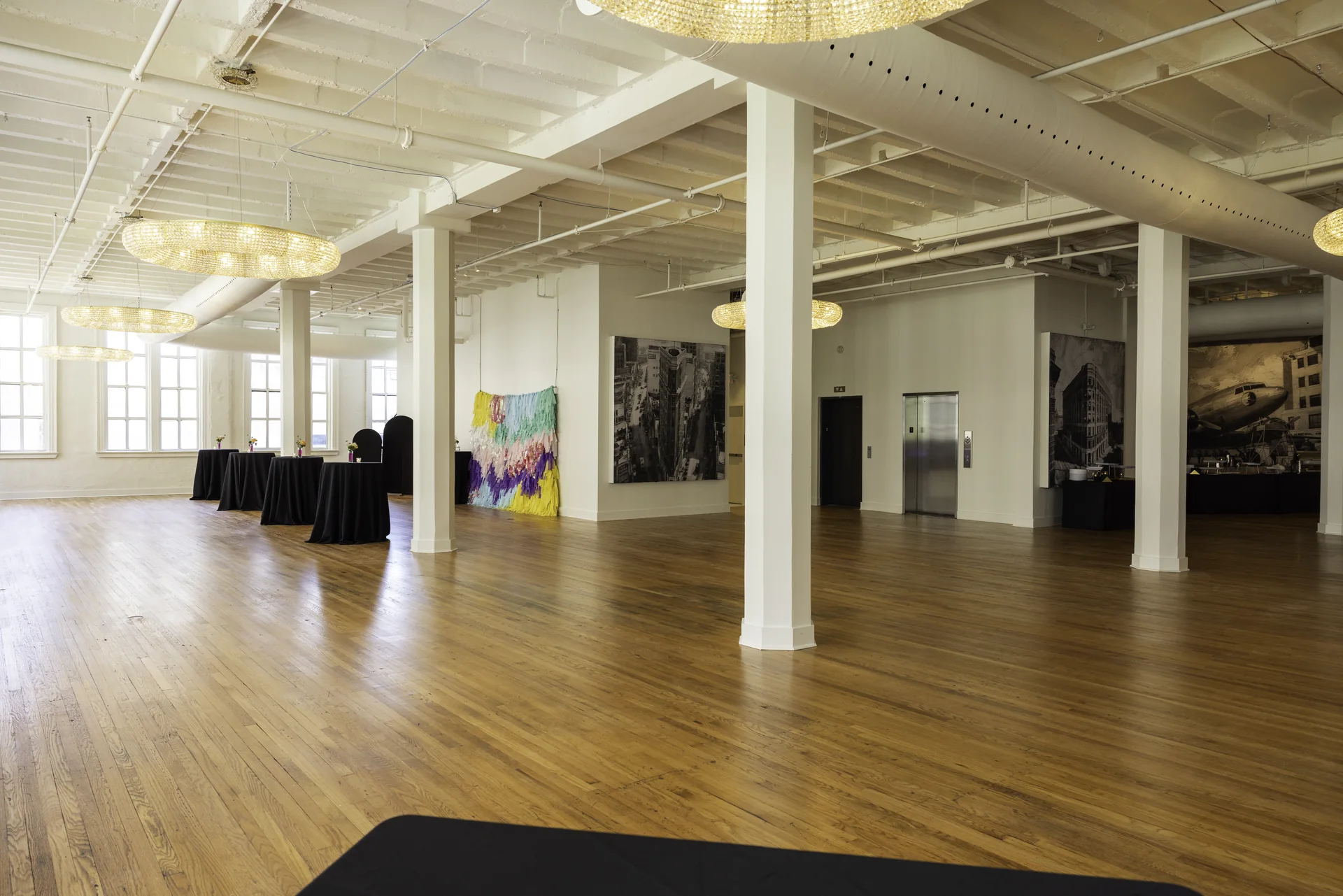 A reverse view across Grand Ballroom’s open floor with a row of columns, windows and the artwork wall.