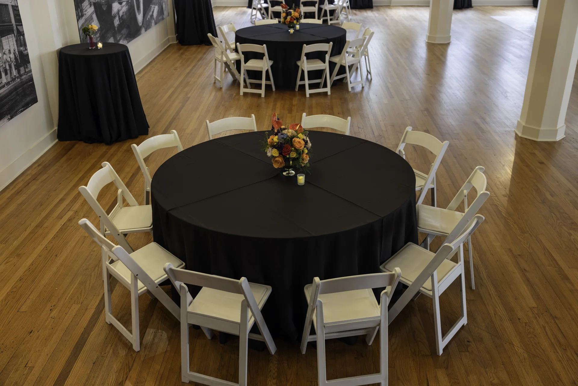 An elevated view of a round table and white chairs inside Grand Ballroom with the bar and windows beyond.