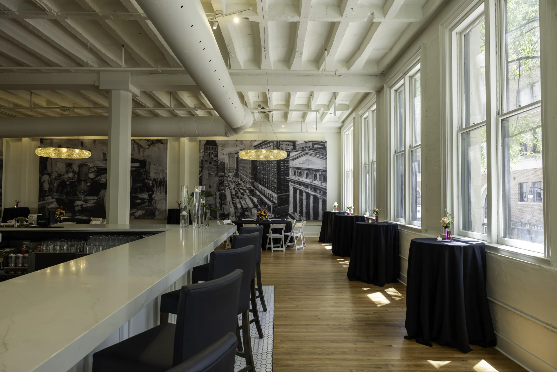 A view along Grand Ballroom’s bar counter and stools beside the tall windows, with the room beyond.